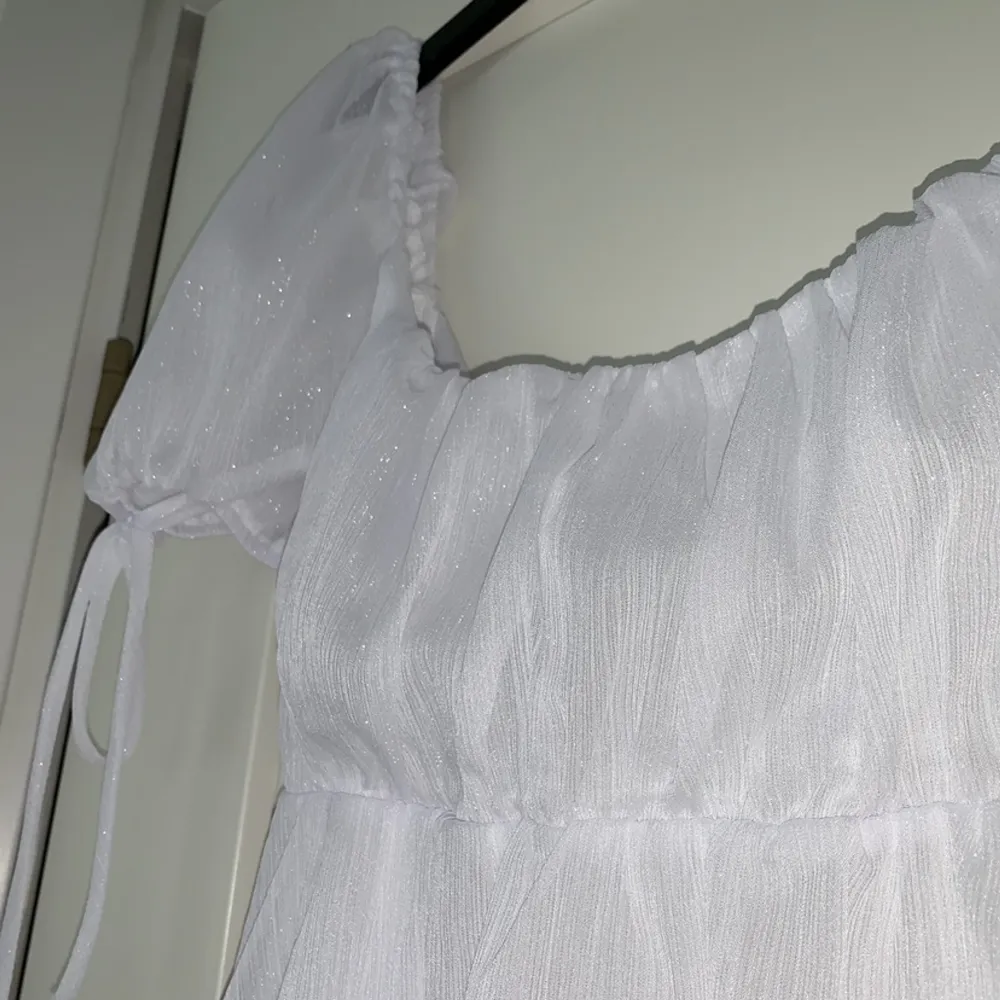 Säljer denna fina vita skimmriga klänning som passar perfekt till studenten! Klänningen har knyte i ryggen och är aldrig använd💓  Jag skulle säga att storleken är mer som en S/M💞. Klänningar.