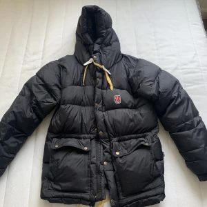 Fjällräven jacka  - Ska sälja min fina svart fjällräven jacka i storlek XS. I jätte fint skick, inga hål däremot sitter ett av de gula banden inte så tight, ni kan se på första bilden 