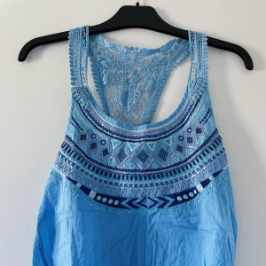 Blått, mönstrat linne - Linne med paljettmönster och brottarrygg i spets. Luftig, vid och väldigt somrig. I fint skick. 