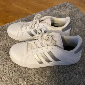 Vita sneakers från adidas med silvrig detalj, använda vid ett tillfälle och säljes då jag överskattat storleken på skorna. 