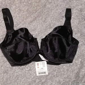 NY BH 85-90 C - Sexig, V formad i mitten, glansig,  ganska "rejäl" i tyget. Helt ny. Märkt 90 C men passar även på 85 c. Avtagbara axelband