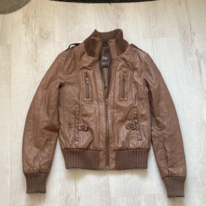 Äkta skinnjacka i bomber modell!  - Läderjacka i brunt med dragkedjor. Fodral & super bekväm och snygg.   Stl 34 , XS