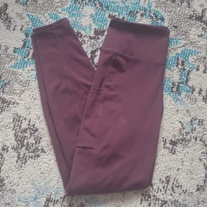Tights - Träningsbyxor från HM i strl S. Vinröda med ficka på höger lår, perfekt för mobilen. Sömmen lite sliten på baksidan annars i bra skick. Hög midja som inte glider ner och går ner till fotlederna. Säljer matchande sportbh från ICIW också.