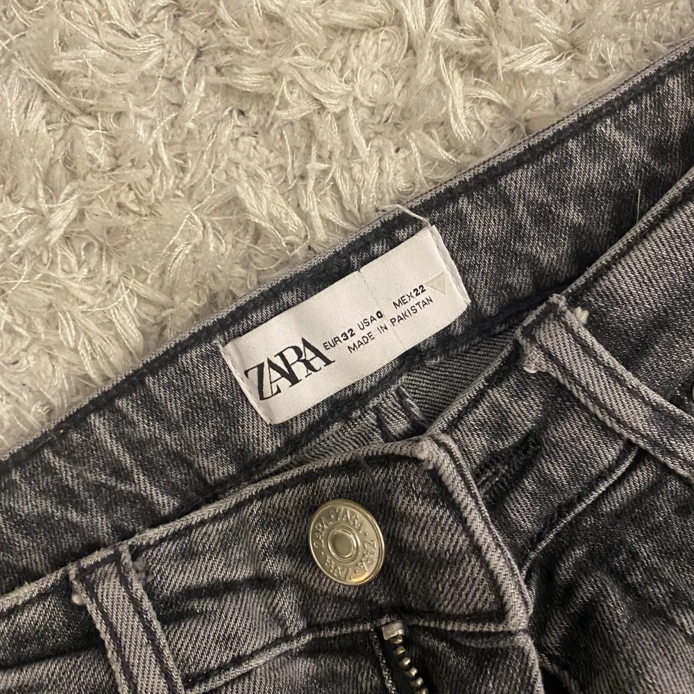Gråa Zara jeans med slits längst ner och medelhög midja. . Jeans & Byxor.
