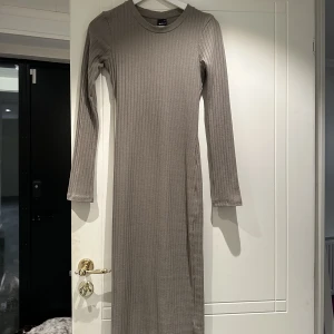 Figursydd maxiklänning - Ribbadklänning med lång arm. Figursydd och tajt. Använt max 2 gånger 