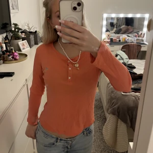 Orangefärgad knapp-tröja - Säljer denna orange-färgade tröjan med 3 st knappar från Lindex. Den har en mer rosa/rödfärg-aktig ton i verkligheten💗knappt använd.