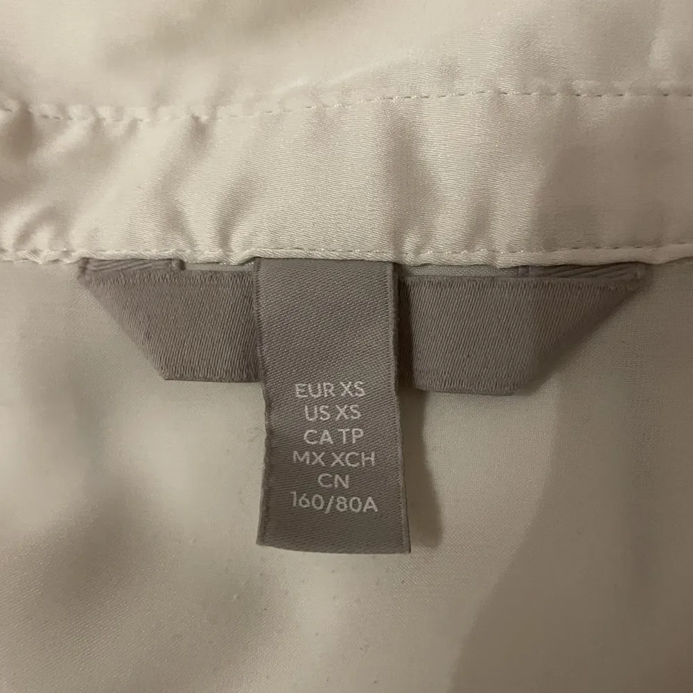 En jättefin, vit satinskjorta från H&M i storlek XS. Den har två små ränder på ryggen som man inte märker så mycket. Kontakta för fler och tydligare bilder 🤍. Skjortor.