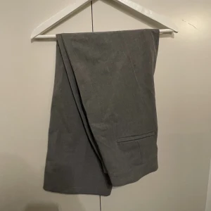 Grå Kostymbyxor (Korta) - Köpta här på plick. Väldigt väldigt korta på mig som är 174 och bär vanligtvis s. Innerbenslängden är 70 cm. Annars väldigt fina😍 Aldrig använda av mig. 