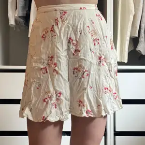 Vit kjol med blommor från Natural Threads i storlek M.  Använda några gånger, därav i fint skick.  Den har knapp och dragkedja i sidan.  Kontakta vid intresse eller funderingar!❤️