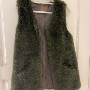 Grön pälsväst - Grön pälsväst från flera år sedan men aldrig använd. Från Zaras barnavdelning men passar mig som har storlek XS/S. Den har två spännen högst upp. Tryck gärna på köp nu knappen! Kontakta för fler bilder.