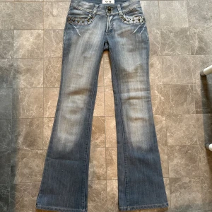 Lågmidjade bootcut jeans - Super coola lågmidjade jeans med nitar vid fickorna, försmå för mig Midjemått: 37cm Innerbenslängd: 82cm 