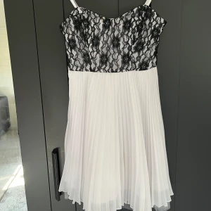 Vit klänning med svart spets - En vit klänning med svart spets. Har avtagbara axelband. Har två ganska små fläckar säljes därför billigt, annars väldigt bra skick.  Storlek 34.  