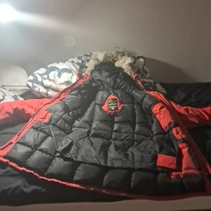 Röd cannada goose jacka - Storlek medium. Munimal skada på söutet av armen och på pälsen vid luvan 