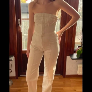 Vit jeans-jumpsuit - Vit, axelbandslös jeans-jumpsuit från Asos, storlek 38. Den sitter bra på någon med långa ben