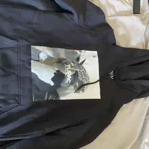 En snygg svart hoodie med tupac tryck på framsidan. Använd men i gott skick.  Passar bra som oversize på XS/S 