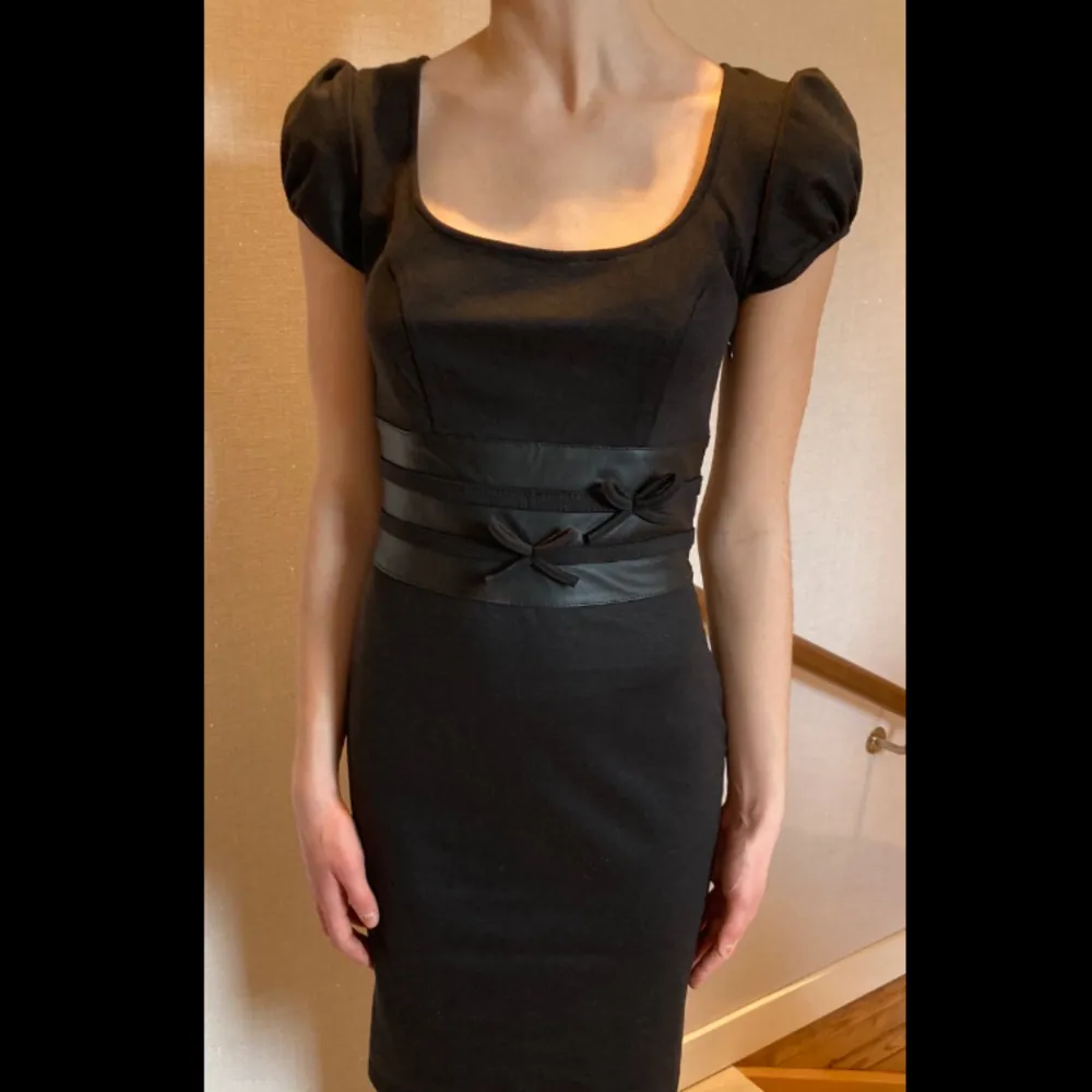  Super snygg svart klänning med läder sträck runt midjan och rvå små rosetter på framsidan🫶🏼 köpte i Barcelona på en elegant klänning butik för 1999kr och säljer nu för 400 eller bud⭐️ Säljer pg av att jag enbart behövde ha den 1 gång så den är som ny!. Klänningar.