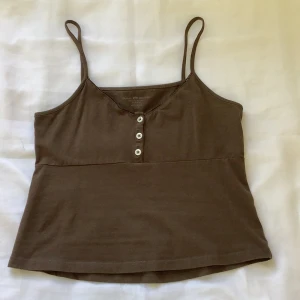 Brunt linne💝 - As snyggt linne från brandy Melville med knappar längst upp i storlek one-size (XS-S)❤️‍🔥 Kom privat för frakten, och hela betalningen sker via swish!