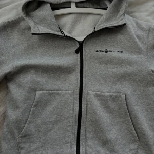 Sail Racing Zip Hoodie Grå - Grå Sail Racing zip Hoodie, bara använd fåtal gånger som ny. BARNSTORLEK 170