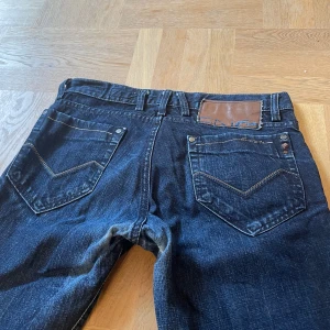 Mörkblå jeansbyxor - Lågmidjade mörkblåa jeansbyxor från märket ”energie”❣️De är en aning slitna i grenen!                  Midjemått= 42 cm                                                              Innerbenslängd= 74 cm                                                   Står ingen storlek men skulle säga att de passar till en S/M