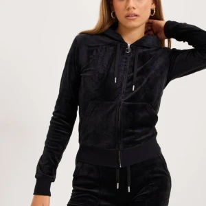 Svart hoodiejacka - En svart hoodiejacka med dragkedja framtill och långa ärmar. Jackan har en huva med dragsko och är tillverkad i ett mjukt material. Juicy Couture, ganska använt men bra skick förutom J:et som är vridet pga fastnat i tvättmaskinen elr nåt, därav de jättebilliga priset