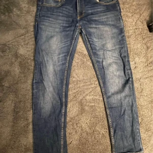 Blå jeansbyxor - Ett par blå jeansbyxor.  Byxorna har en klassisk femficksdesign och med normal passform.