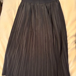 Svart plisserad kjol - En elegant svart plisserad kjol med hög midja. Kjolen har en klassisk design och är perfekt för både vardag och fest. Stor i storleken ❤️
