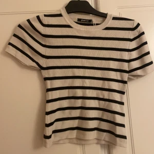 Stickad tshirt - Trendig finstickad randig tshirt , väldigt fin i storlek M passar även S , sitter väldigt fint men tyvärr för liten för mig , säljer T-shirten för 90 kr