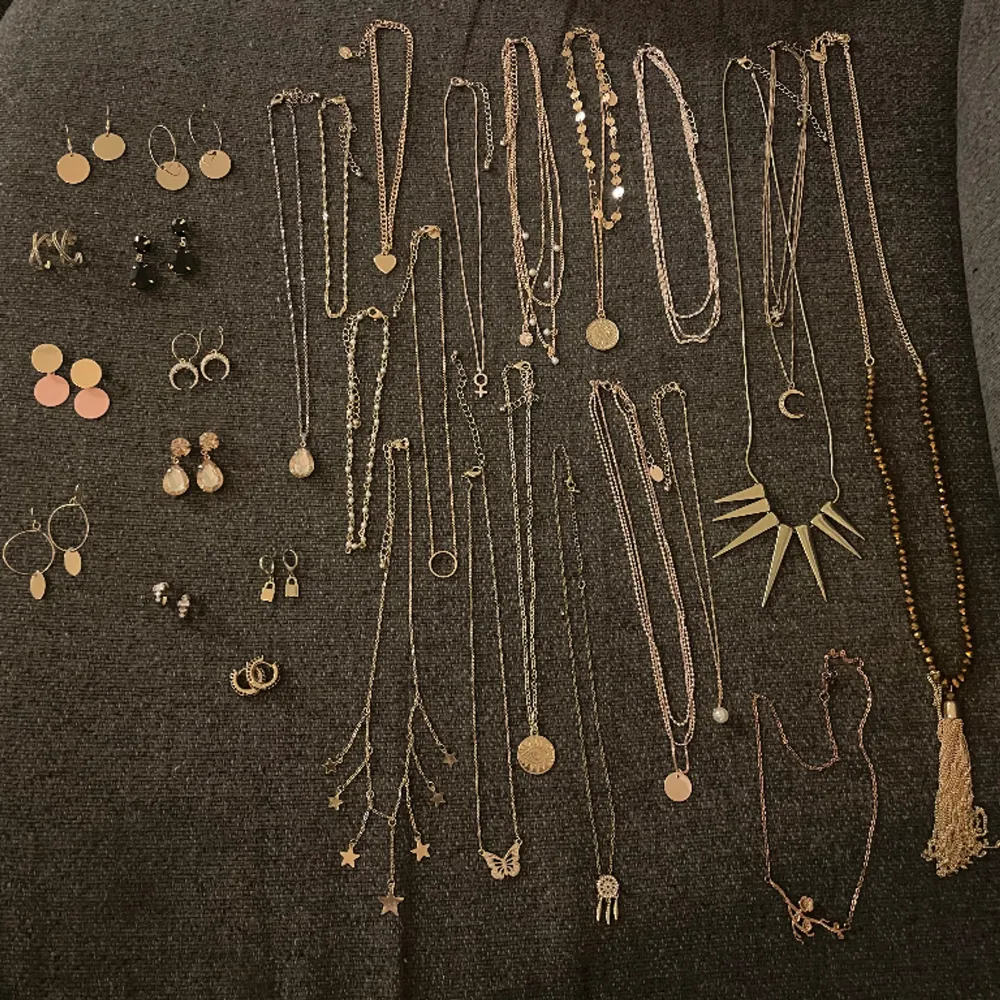 Ett smyckespaket med halsband con örhängen. 11 par örhängen och 19 par halsband. Guldfärgat. Accessoarer.