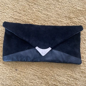 Kurvert skinnväska - Kurvert väska i skin med dragkedja. 