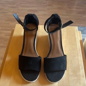 Svarta klackskor - Sandaletter i svart med kilklack. Från H&M i storlek 36. Har endast provats så de är i nyskick.