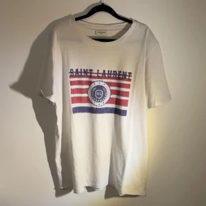 Saint Laurent T-shirt  - Säljer denna Saint Laurent T-shirten som är i 8/10 skick. De enda defekterna är att det kragen har ett pyttelitet hål, kom dm om ni vill se. Annars toppskick!✅