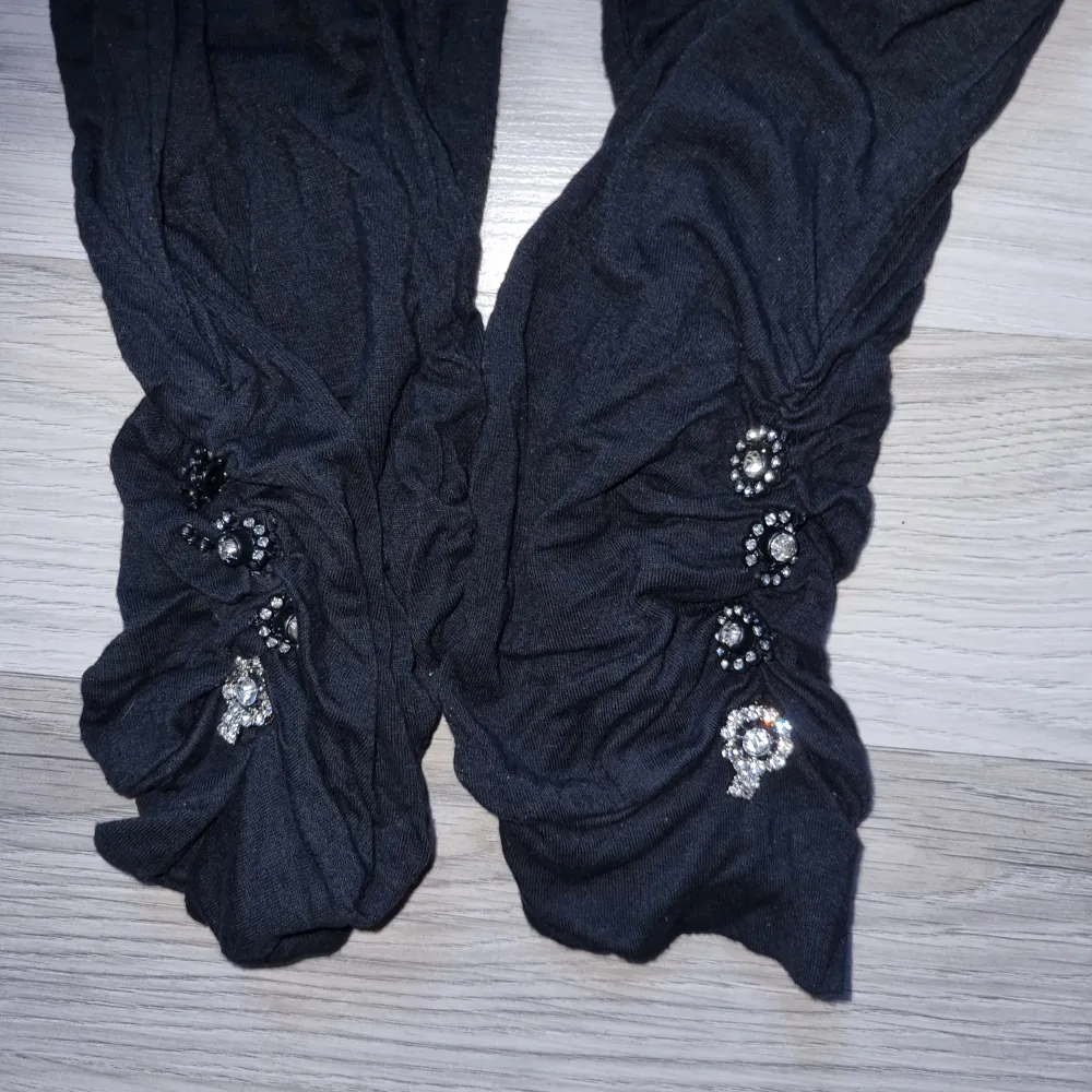 Svarta leggings med elastisk midja och dekorativa detaljer vid bensluten. Byxorna har en lös passform och är dekorerade med pärlor och blingbling. stl 146/152. Jeans & Byxor.