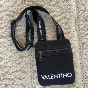 Valentino väska - Valentino väska som nästan aldrig har använts. Väskan är i mycket bra skick. Den har ett stort fack både fram och bak, även två inuti. Axelremmen kan du justera själv. Köpt på Zalando för ca 800kr 