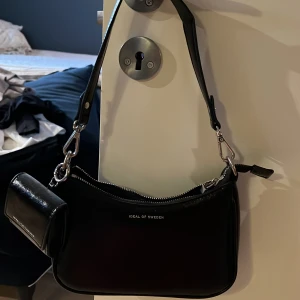Svart Väska  - Väska från Ideal of Sweden med silverdetalj och separat väska till AirPods sitter på köpt för ca 1000 säljer för 450