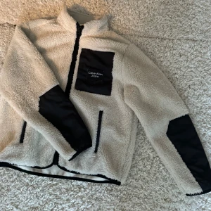 Calvin Klein flis fluffig - En fin vit och svart Calvin Klein flis, den är mycket varm och gosig, väldigt skön! Använd några få gånger, i bra skick!