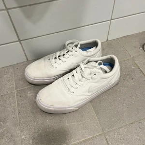 Vita Nike sneakers - Säljer mina vita sneakers från Nike i storlek 38,5. Jättesköna och passar till allt, nån ljus fläck fram på skon som man ser på bilderna, och snörena är avklippt för att kunna ha de i skon💕