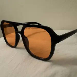 Oanvända svarta solglasögon med orange glas 