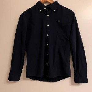 Tommy hilfiger skjorta - Säljer min Tommy Hilfiger skjorta då den inte kommer till användning. Mycket fint skick. Nypris 600 mitt pris 250 men pris kan diskuteras. Storleken på skjortan är 152 till 160. Skriv gärna vid fler frågor eller bilder.