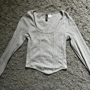 Oanvänd topp - Korsettliknande topp, ljusgrå i storlek S. Endast testad så oanvänd.   Säljer för 100 kr, hämtas i Kalmar eller skickas mot fraktkostnad. 