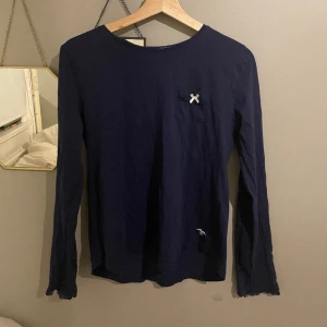 Tröja - Blå långärmad tröja från Hampton Republic. Riktigt söt ficka på framsidan med en rosett. Knappt använd och det finns inga defekter eller annat. Jätte söt spets i slutet på ärmarna.