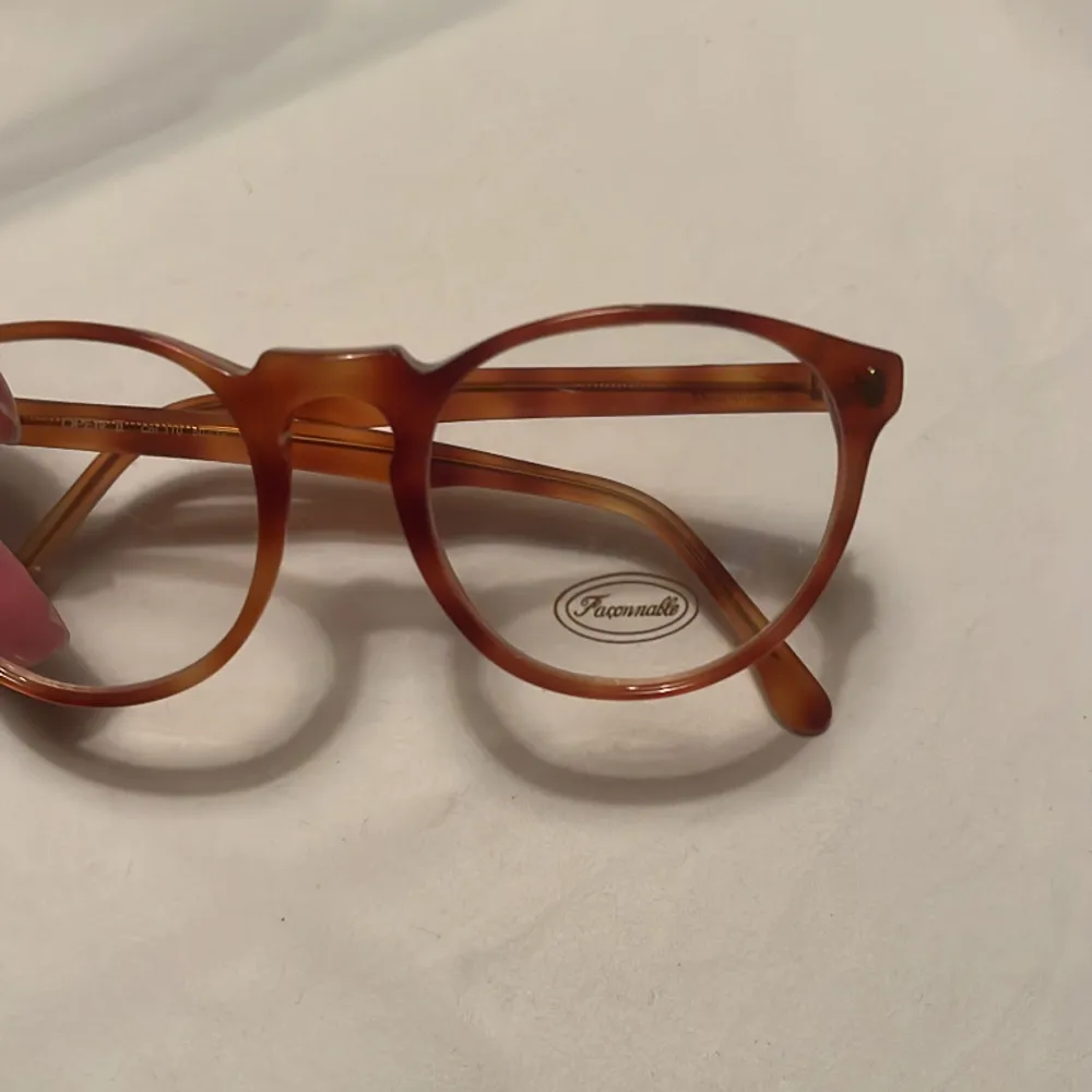 Exklusive glasögonbåge från Faconnable från 80 Talet, ljusbrun melerad Kommer från en nedlagd Optikbutik, aldrig använd Hela bågens bredd 130 mm Glasets storlek, bredd 49 mm, djup 45 mm . Asusteet.