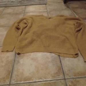 Ny tröja  - Nyinköpt samt oanvänd tröja. Baksidan är den korsad. Färg skulle jag säga aprikos/ kaki. På beskrivningen av tröjan står det aprikos.