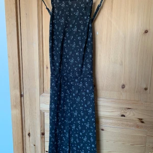 Blommig klänning - Småblommig klänning i svalt material från italienskt märke. Svår att mäta och fota då den är öppen i ryggen samt har korsade band. Banden är även justerbara. Märkt storlek M men skulle säga att den passar S, den har en del stretch. Aldrig använd.