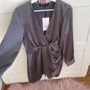 Zara satin klänning  - Jätte snygg kort oanvänd zara satin klänning i grå, den är i storlek M men den är för liten för mig som brukar ha storlek 38. Jag tror den passar mer som S. 