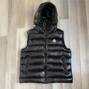 Moncler väst - Säljer nu min moncler väst i size 3  skulle säga att den motsvarar S. Svart glansig med luva, två sidofickor på utsidan och en innerficka. Det är unisex så passar till både killar och tjejer. Hör av er på pm om ni har frågor 😊