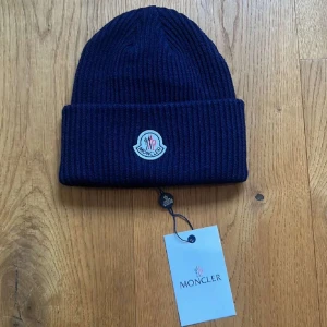 Moncler mössa - Moncler mössa skick 9/10 fick den i present och passade inte min stil taggar finns kvar och scan fungerar såklart skriv för mer frågor!
