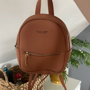 Mini ryggsäck - En mini ryggsäck som är köpt i Thailand, har aldrig använt den så den är i helt nyskick! Färgen är lite nude/rosa