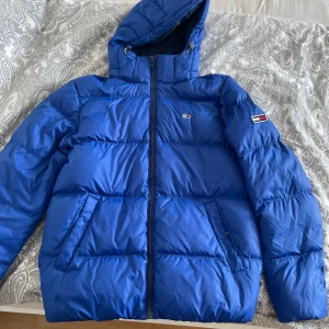 Blå Tommy jeans jacka herr - Använd 1 vinter. Säljer åt pojkvännen. Nypris 2600kr. Så gott som ny, använd varsamt och nyligen tvättad.  Normal passform 