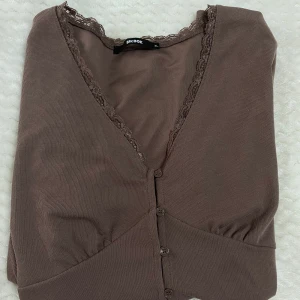 Tröja - Brun urringad Tröja i storlek (XL). Tröjan har knappar som kan öppnas och stängas.  Andvänts ett par gånger.