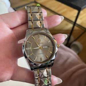 Säljer denna helt ny klocka med box märke BINBOND QUARTZ unisex tror jag den har små strass detaljer och även datum ej använd plastplupp kvar plus plast vid spänne insida riktigt fin färg silver med guldiga detaljer 